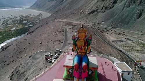 établissement d'une vue aérienne d'une grande statue de Bouddha en or, située au milieu d'un val de montagne