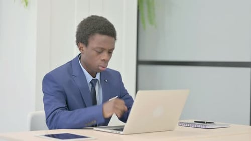 Young Adult Coughing at Desk in Office