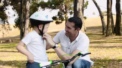 Father teaches son bicycle safety on a sunny park pathway adventure