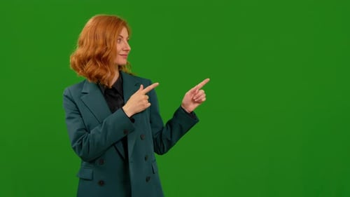 Frau lächelt und schaut in die Kamera und zeigt mit dem Finger auf die linke obere Seite über einem Greenscreen-Hintergrund