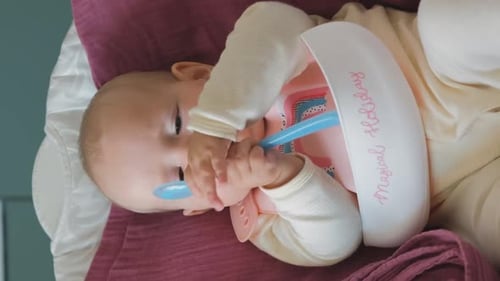 Cute Baby Chewing On Blue Spoon at Home