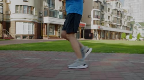 Side View of Motivated Sporty Fit Man Practicing Morning Jog in City at Dawn