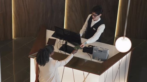Woman Checks in at Sleek Hotel Reception Desk
