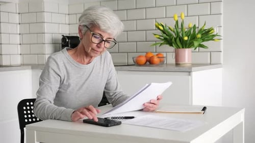 Mulher aposentada sênior calculando valores de pagamento no contrato de crédito