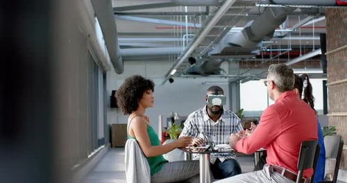 African american businessman wearing vr headset while colleagues watching him at office