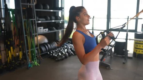 Young Athletic Woman Doing Exercises with Trx Fitness Straps in the Gym
