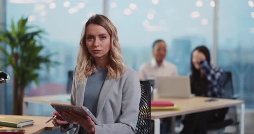 Woman using Tablet in Office with Colleagues