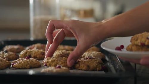 Biscuit. A mature woman in kitchen clothes puts finished baked goods on a plate on the kitchen table