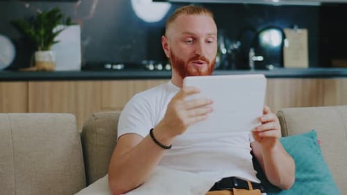 Smiling Man Video Calling on Tablet at Home