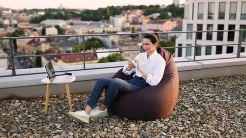 Woman Relaxing on Rooftop Using Smartphone