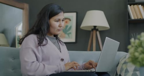Woman Working on Laptop at Home on Couch