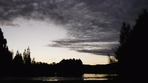 Flash of orange underneath the clouds during a time lapse of the sun setting.