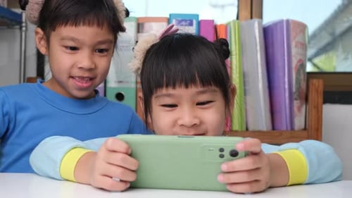 Cheerful Children Using Smartphone Indoors