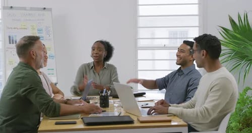 Group of diverse businesspeople giving each other high five during meeting in an office boardroom