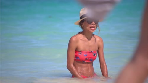 Happy thin latin woman wearing a bikini a hat and sunglasses enjoying the calm sea of Cancun