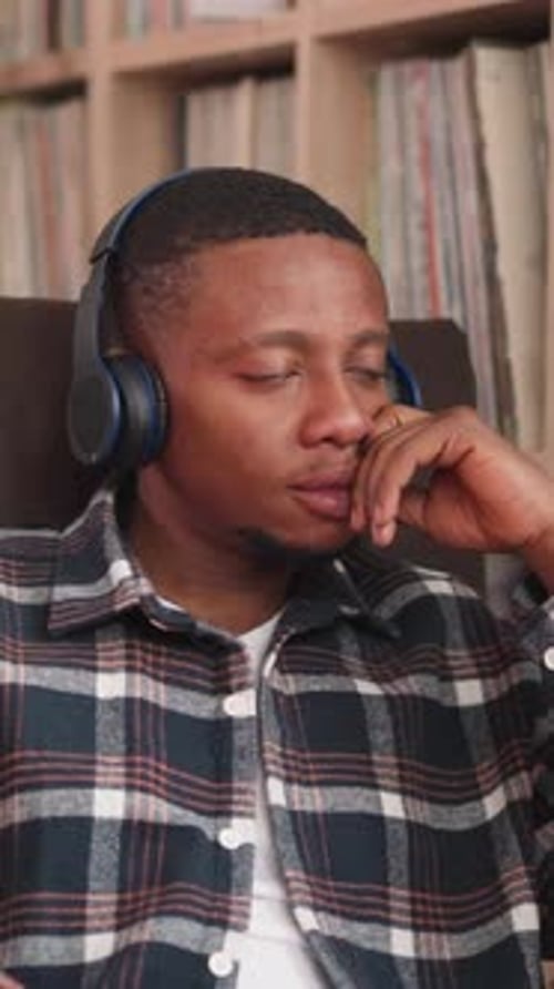 Man Listens to Music Via Headphones in Library