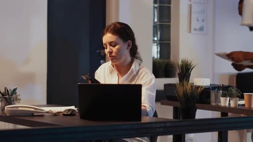 Woman Answers Phone While Working at Desk