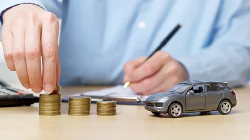 Concept of buying a car on credit, insurance. Hand stacking coins as accumulation of money.
