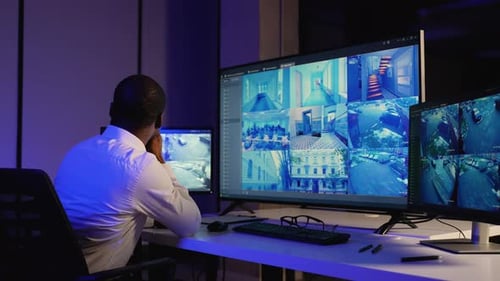 Man Monitors Security Cameras in a Control Room