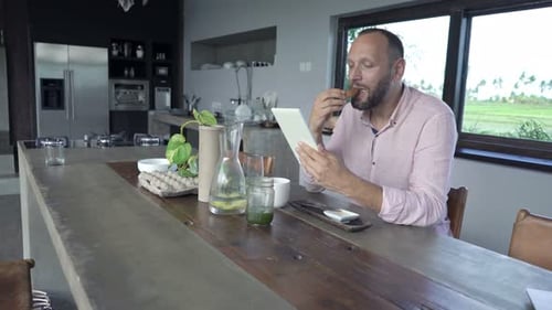 Man Eats and Uses Tablet Device at Table