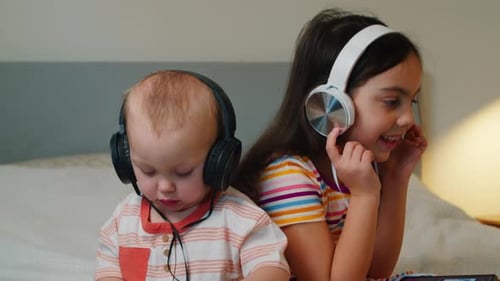 Two Cute Cheerful Children in Headphones Listen to Music