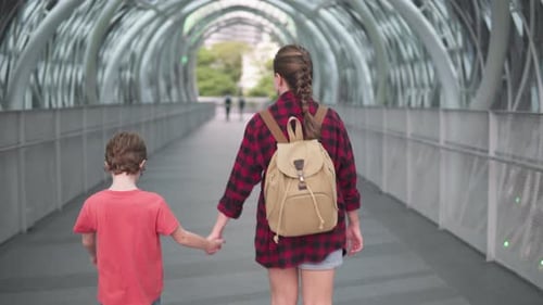 Woman and little boy are walking through a covered bridge