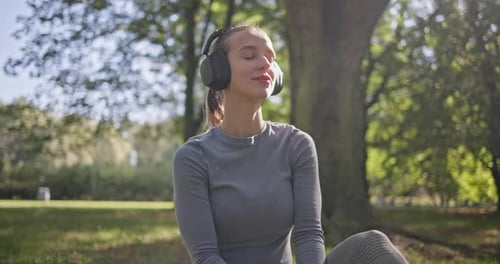 A Young Beautiful White Girl Practices Yoga in the Park and Meditates in the Lotus Position Among