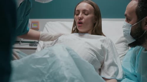 Schwangere Frau schubst und Hebamme holt Baby während der Wehen heraus