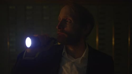 Man with Flashlight Walking in Dark Hallway at Night