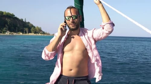 Young Man Talking on Cellphone While Sailing Boat on Sea 30s