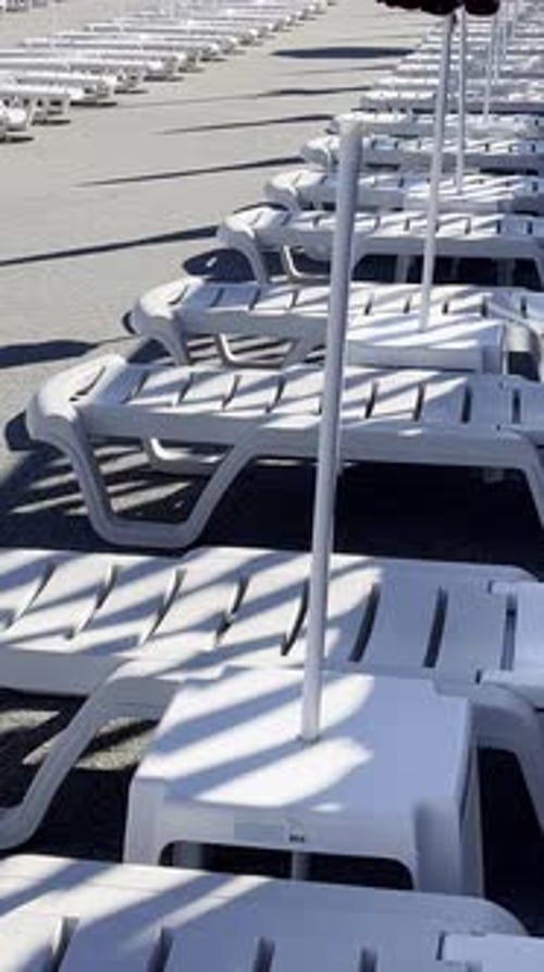 Empty Sun Loungers Under Sunshades at a Resort Poolside Area