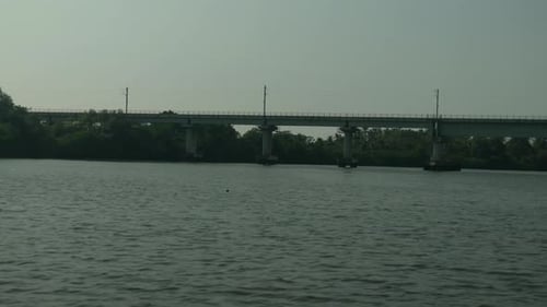 Ponte ferroviária sobre rio calmo, vegetação exuberante nas margens, ambiente sereno, dia claro