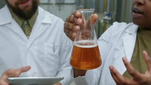 Anonymous Technologist Holding Flask with Fresh Beer Sample