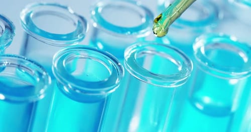 Yellow Liquid Dripping into Blue Liquid in Test Tubes