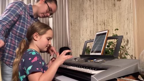 Girl Plays Piano With Teacher in Living Room