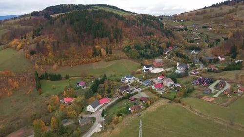 Aerial View of Colorful Autumn Forest Near Mountains and Village in Fall Season