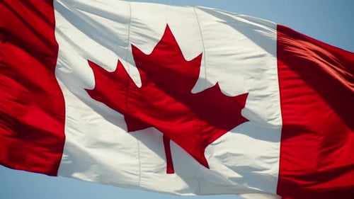 Canadian Flag Waving Against Blue Sky