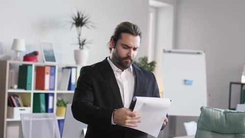 Man Reading Documents on Clipboard in Modern Office Room