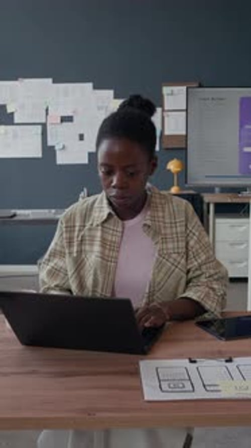 Portrait of Happy Black female UI Designer Using Laptop at Office