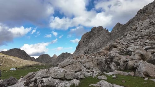 Zeitraffer: Ein Weitwinkelblick auf eine raue, felsige Berglandschaft mit einem kleinen Campingzelt