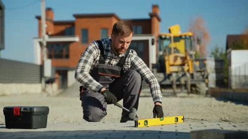 Construction Worker Laying Pavers on Sunny Day