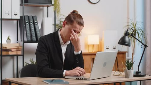 Exhausted Young Businessman Using Laptop Taking Off Glasses Massaging Dry Irritable Eyes at Desk