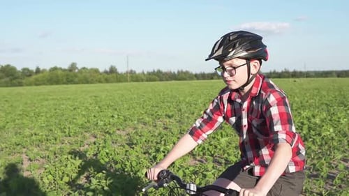 A Boy in a Helmet Rides a Mountain Bike in the Park
