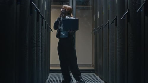 Concentrated Female Data Center Administrator Checking Rack Server Cabinets