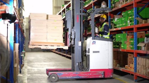 Warehouse worker controlling forklift in warehouse