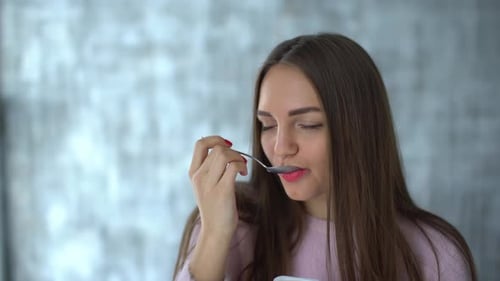 Woman with Long Brown Hair Eating Yogurt Inside