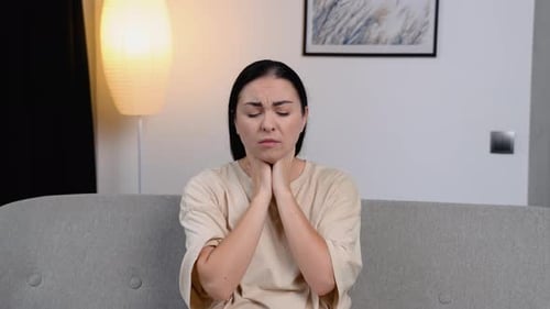 Woman Massaging Sore Neck While Sitting on Couch