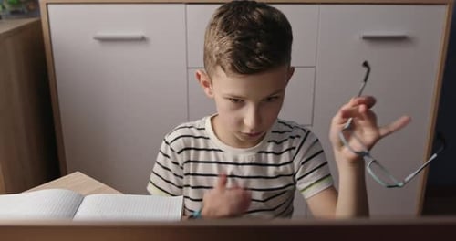 Boy With Glasses Studying At Desk