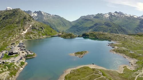 Orbit over mountain lake on Grimsel Pass in the Swiss alps, with view of the pass road and hotel.