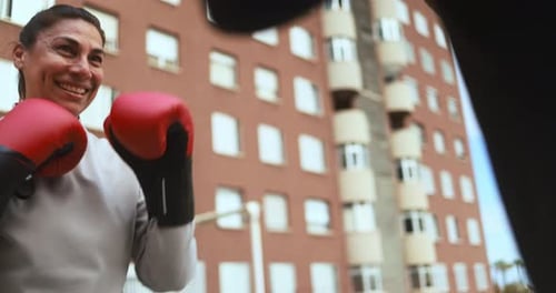 Smiling Woman Boxing with Red Gloves in City
